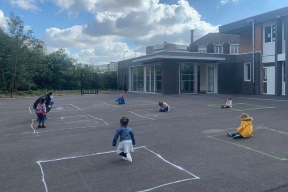 Crianças brincam na escola limitadas por quadrados desenhados a giz no chãoq