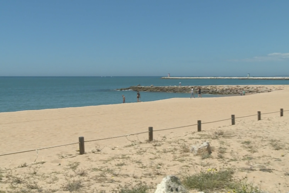 Areal da praia de Quarteira quase vazio em dia de calor. População aproveita paredão para caminhar