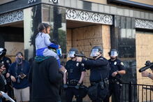 Foto mostra polícia de arma apontada a criança às cavalitas do pai