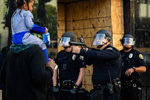 Foto mostra polícia de arma apontada a criança às cavalitas do pai