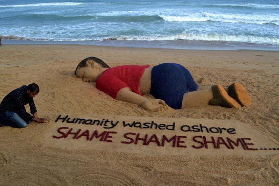 O artista indiano Sudarsan Pattnaik trabalha em uma escultura de areia que representa o menino sírio Alan Kurdi 