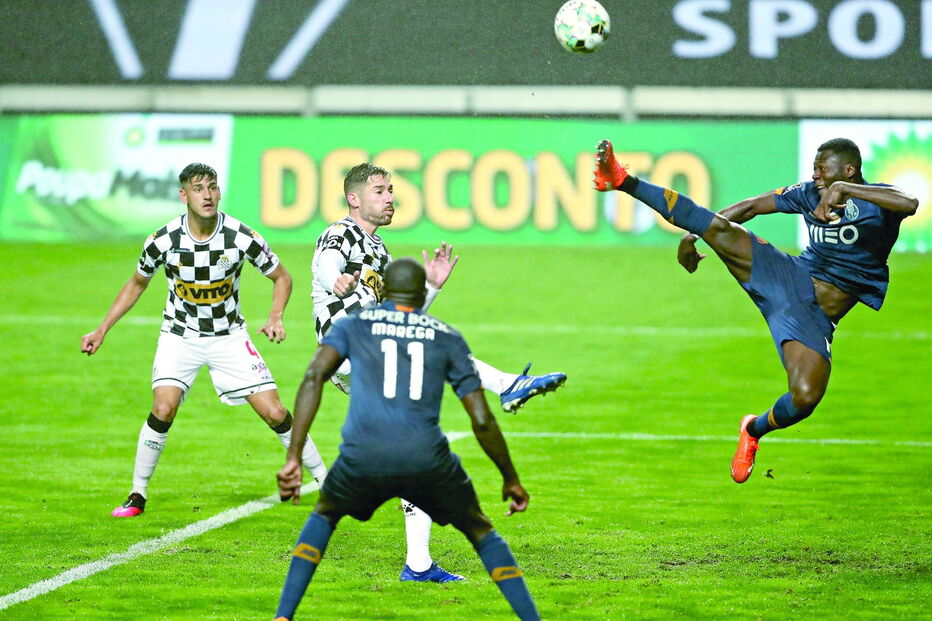 Mbemba surge em pose acrobática perante o olhar atento do colega Marega e a aproximação de Javi García, do Boavista 