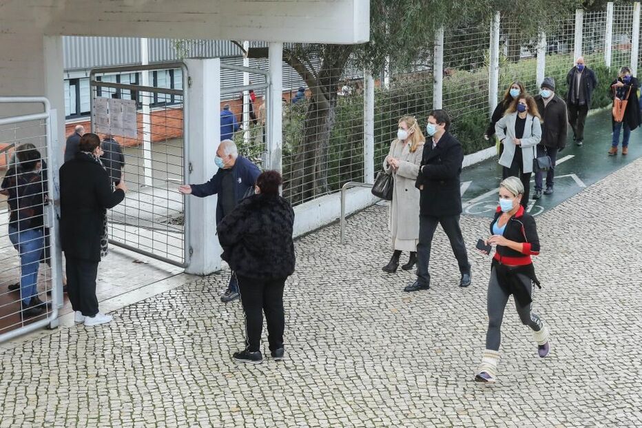 Populares aguardam numa fila no exterior da Escola Secundária António Damásio em Lisboa, 24 de janeiro de 2021
