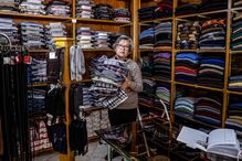 Uma funcionária arruma camisas na Casa Verde, na baixa de Faro, 15 de abril de 2021. O comércio local na baixa de Faro procura resistir às restrições impostas pelo combate à pandemia de covid-19 e mesmo a centenária Casa Verde, a loja há mais tempo em atividade no centro da cidade, mantém as portas abertas, com planos para o futuro