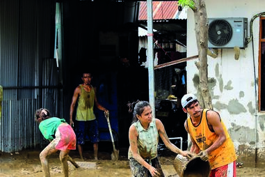 Populares limpam a lama arrastada pelas cheias em Díli