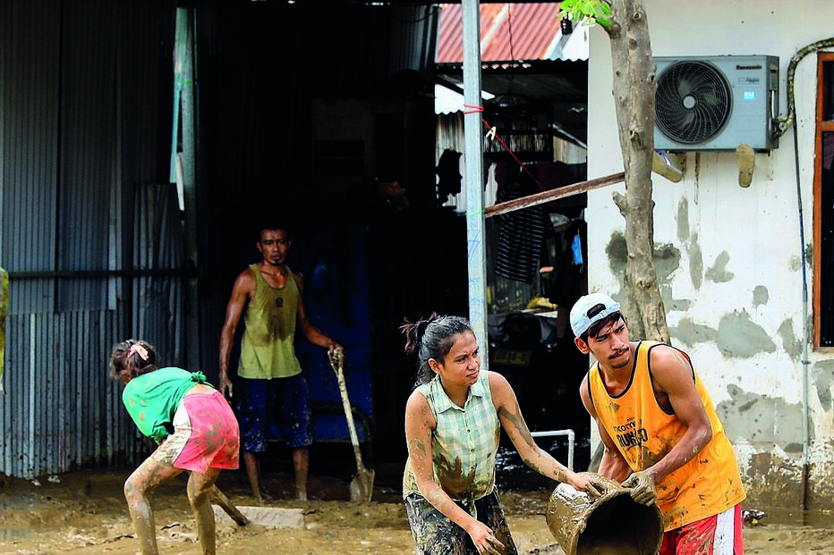 Populares limpam a lama arrastada pelas cheias em Díli