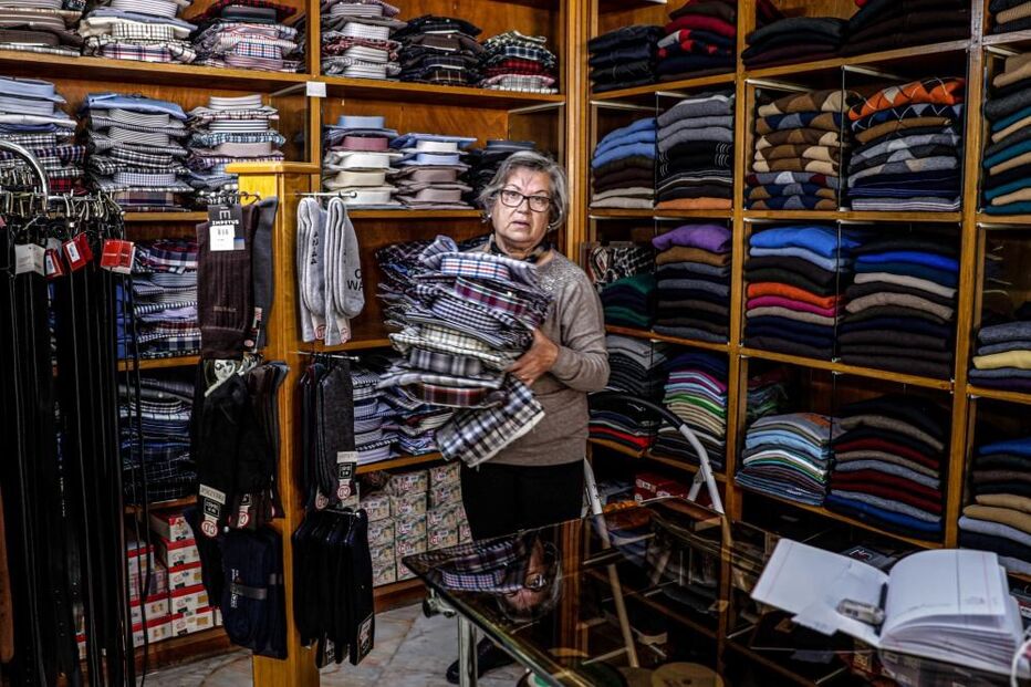 Uma funcionária arruma camisas na Casa Verde, na baixa de Faro, 15 de abril de 2021. O comércio local na baixa de Faro procura resistir às restrições impostas pelo combate à pandemia de covid-19 e mesmo a centenária Casa Verde, a loja há mais tempo em atividade no centro da cidade, mantém as portas abertas, com planos para o futuro