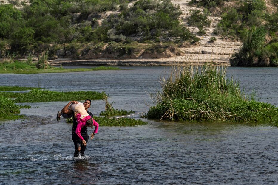 Jovem carrega ao colo idosa de 80 anos para atravessar o rio que separa os Estados Unidos do México