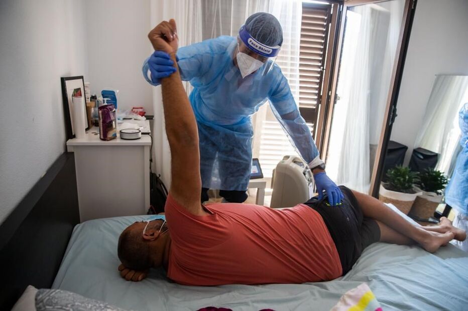 Enfermeiro da Unidade de Hospitalização Domiciliária do Hospital Garcia de Orta, Filipe Dias, ensina exercícios respiratórios a Jair, um paciente internado em casa com Covid-19, na zona do Seixal
