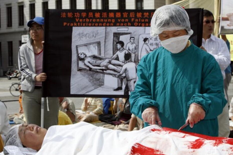Um manifestante vestido como um médico chinês simula a remoção de órgãos de outro vestido como seguidor do movimento Falun Gong num protesto em Berlim, Alemanha, em 2007