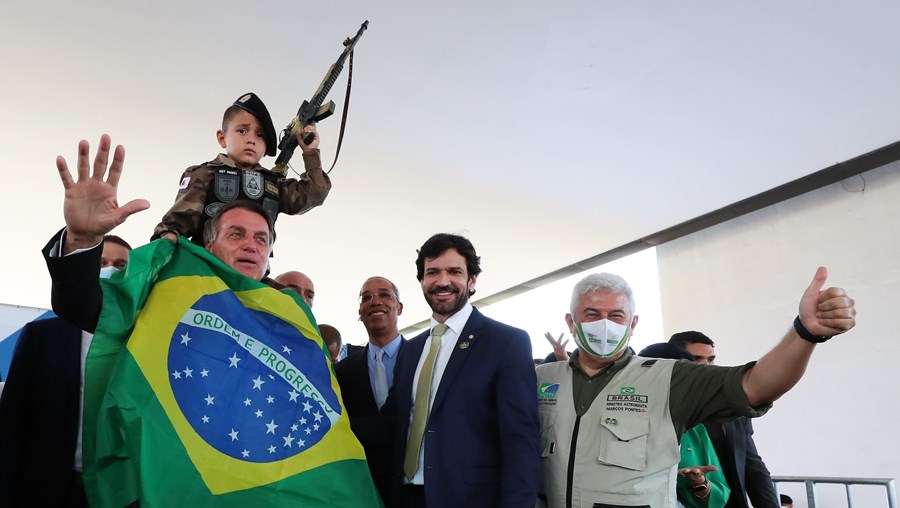 O presidente Jair Bolsonaro posa com uma criança empunhando uma arma, numa ação política em Belo Horizonte