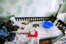 Quarto de uma criança, onde são visíveis alguns brinquedos e uma guitarra