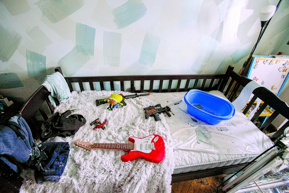 Quarto de uma criança, onde são visíveis alguns brinquedos e uma guitarra
