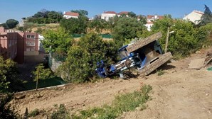 Máquina de obras com várias toneladas cai e destrói muro de casa em Lisboa