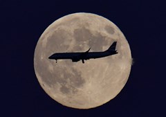 Um avião de passageiros é visto a passar em frente à lua, conhecida como 'Lua d eMorango', em Londres, no Reino Unido