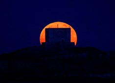 A lua de morango ergue-se atrás da Torre de Santa Marija, na ilha de Comino, em Malta