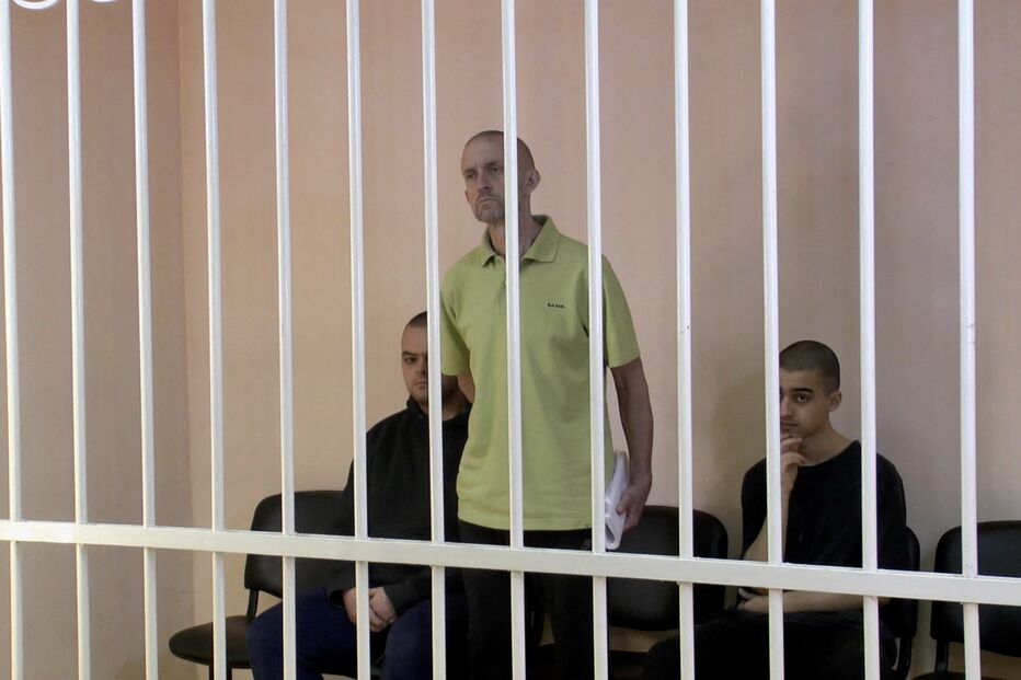 Britânicos Aiden Aslin e Shaun Pinner e o marroquino Brahim Saadoun numa cela no tribunal em Donetsk