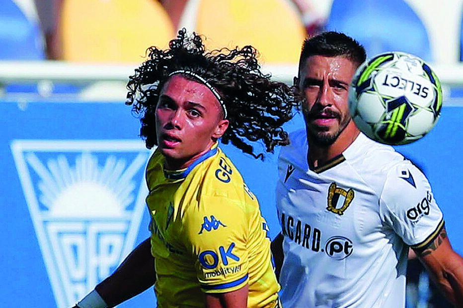 Gonçalo Esteves (Estoril) olha para a bola, tal como Rui Fonte (Famalicão)