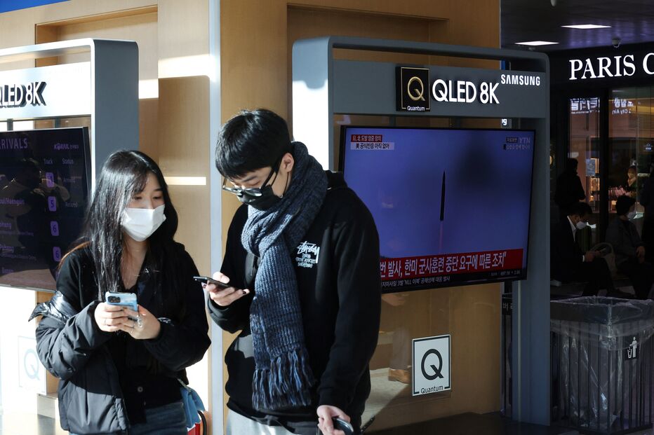 Um casal olha para os telemóveis ao lado de uma TV que transmite uma reportagem sobre a Coreia do Norte que disparou um míssil balístico na costa leste, em Seul, Coreia do Sul
