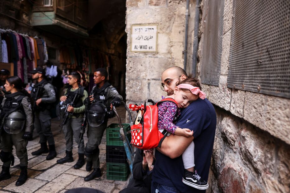 Um homem segura uma bebé na área do incidente fatal de esfaqueamento, na Cidade Velha de Jerusalém
