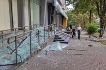 Funcionários limpam as janelas partidas de uma loja danificada durante um ataque de mísseis russos em Kiev