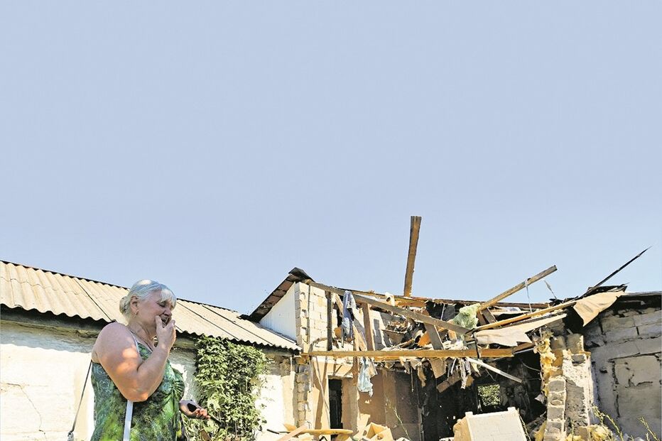 Uma mulher junto aos destroços de uma casa atingida pela artilharia russa na região de Donetsk
