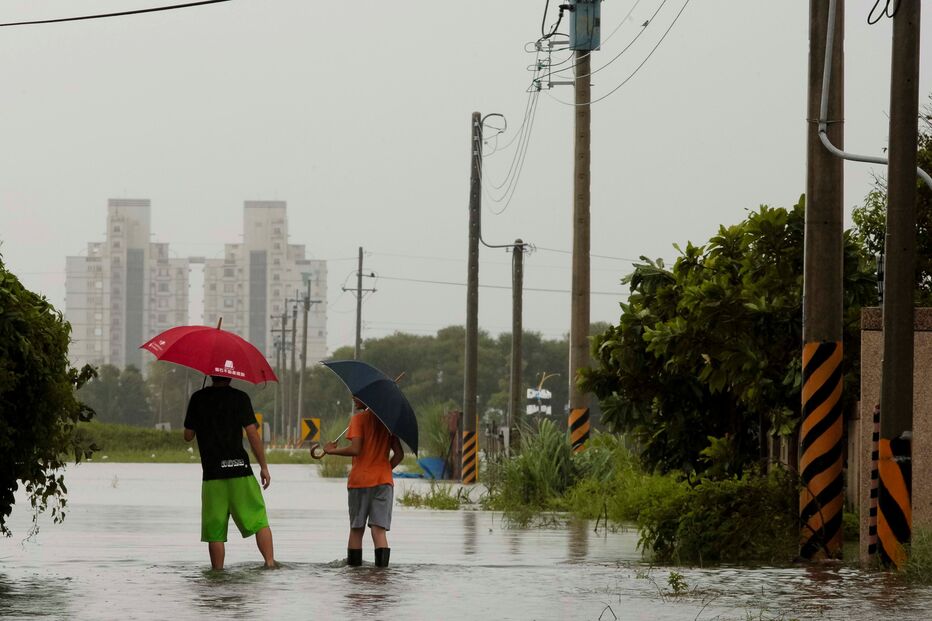 Jovens caminham numa estrada inundada pelo tufão Saola em Wujie, Taiwan. Tufão dirige-se para Macau