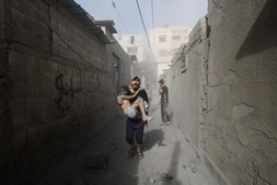 Homem palestiniano carrega criança ferida na Faixa de Gaza durante ataque israelita 