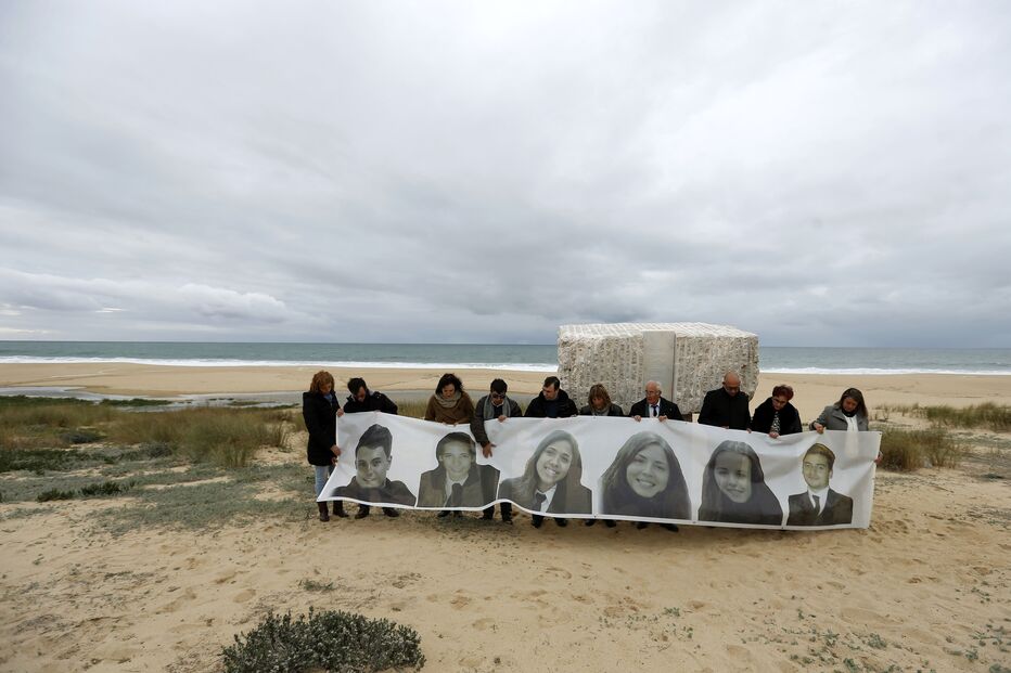 Familiares das seis vítimas junto ao memorial, na praia do Meco, com uma tarja com as imagens das vítimas