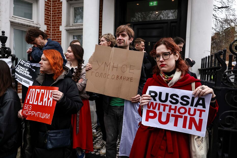 Pessoas seguram cartazes no último dia das eleições presidenciais na Rússia em Londres
