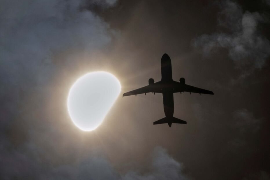Uma avião passa durante o eclipse solar parcial em Nova Iorque