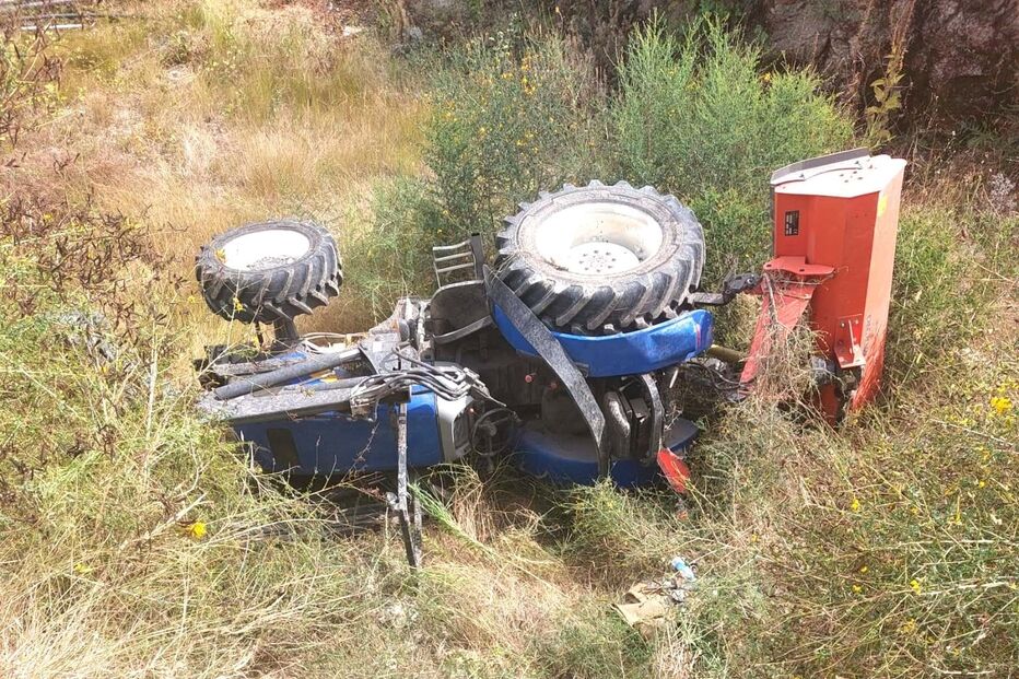 Trator capota e cai de muro de três metros