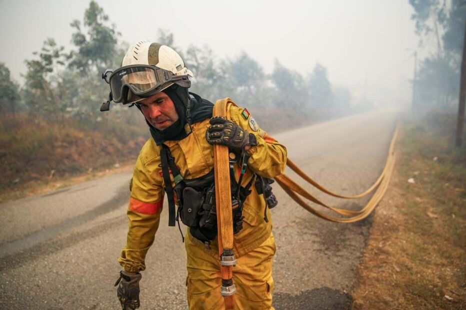 bombeiro transporta uma mangueira durante durante o combate ao incêndio em Águeda
