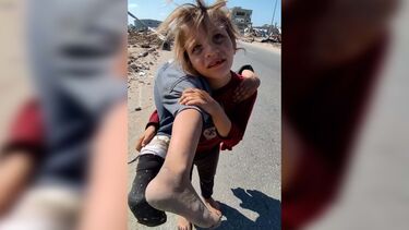 Menina descalça carrega às costas irmã ferida em atropelamento em Gaza