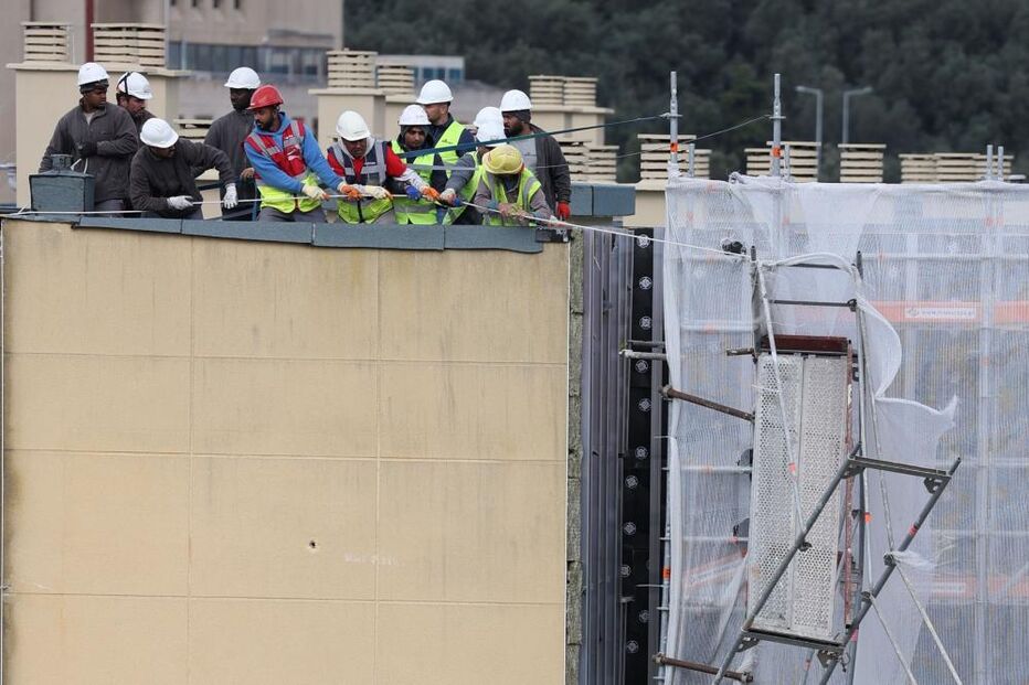 Funcionários tentam puxar parte de uma estrutura em andaimes que desabou devido à passagem da tempestade Martinho, em Lisboa