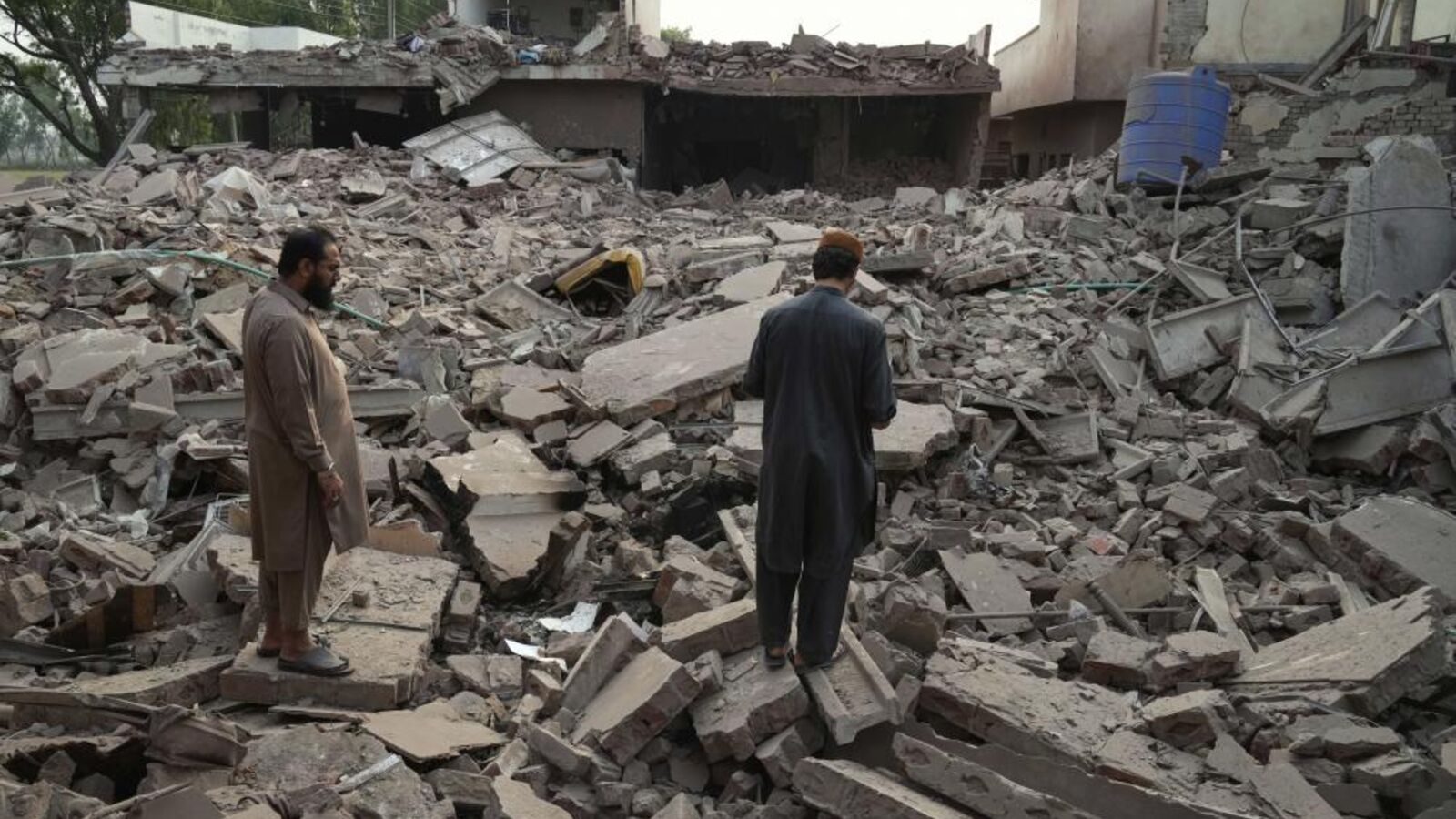 Populares entre os escombros de edifício atingido por mísseis indianos na província paquistanesa do Punjab