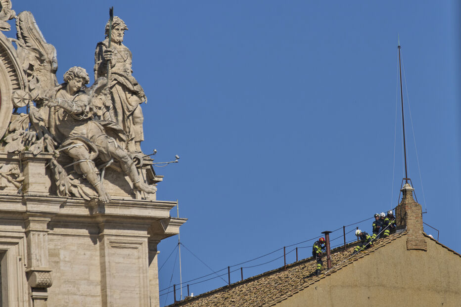 Bombeiros colocam a chaminé no telhado da Capela Sistina