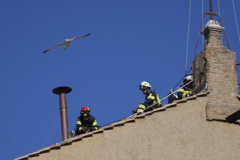Bombeiros colocam a chaminé no telhado da Capela Sistina