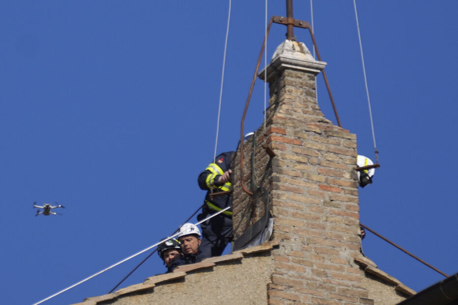 Bombeiros colocam a chaminé no telhado da Capela Sistina