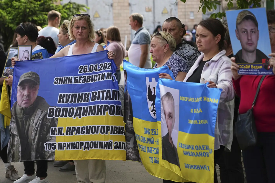 Familiares de prisioneiros ucranianos com faixas e fotos de militares em cativeiro antes da troca de prisioneiros, na região de Chernyhiv, Ucrânia
