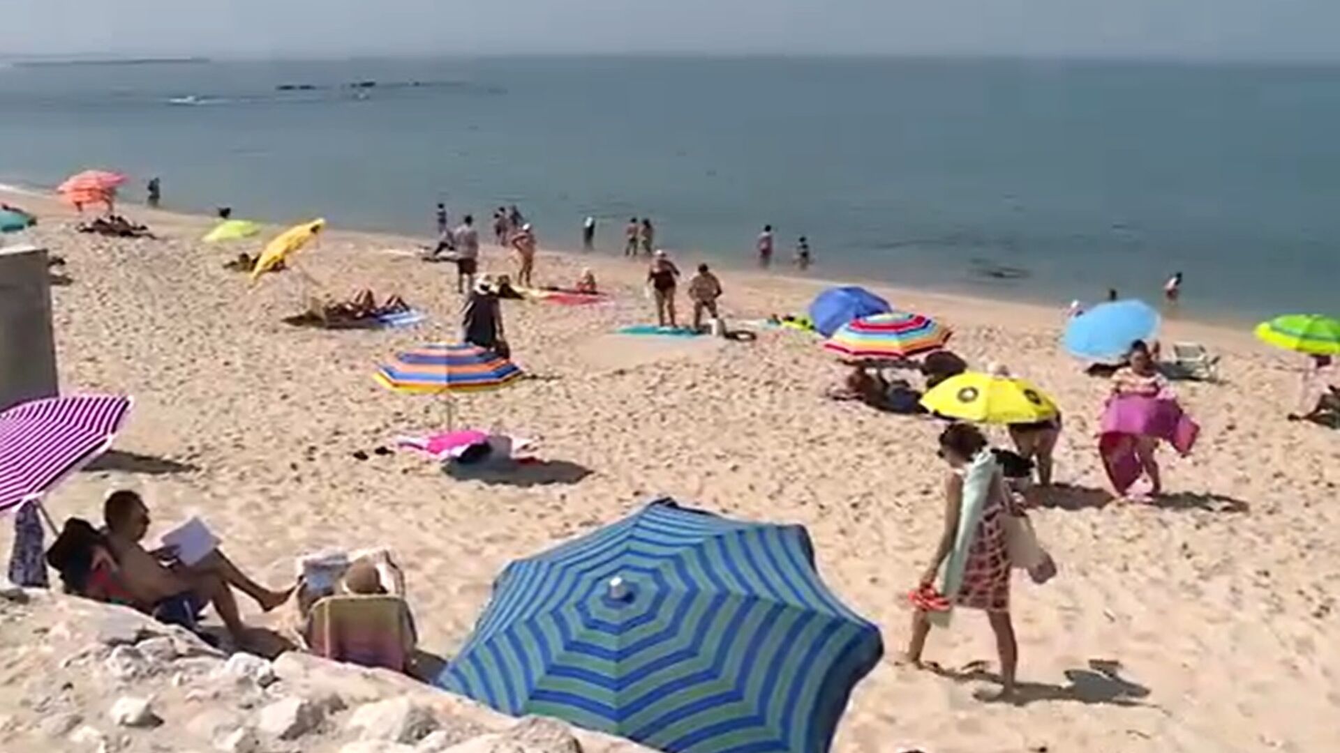 Várias pessoas aproveitam o mar calmo e o céu limpo na praia da Figueira da Foz