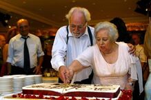 Casal corta bolo comemorativo em festa