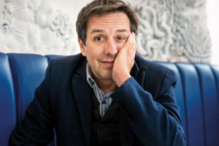 Retrato de homem com blazer azul num sofá acolchoado azul