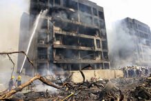 Bombeiros combatem incêndio em edifício danificado, com destroços no local