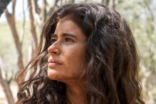 Atriz caracteriza personagem em cenário de vegetação seca