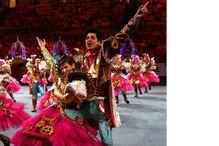 Pessoas atuam em evento cultural, vestidas com fantasias elaboradas e coloridas