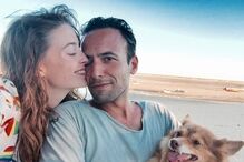 Um casal e um cão numa praia aproveitam o dia