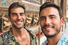 Dois homens sorriem em frente ao templo Wat Arun Ratchawararam Ratchawaramahawihan, em Bangkok