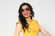 Mulher sorri com óculos de sol e vestido amarelo