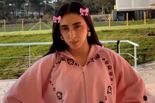 Mulher posa com adereços de cabelo e casaco rosa num espaço exterior